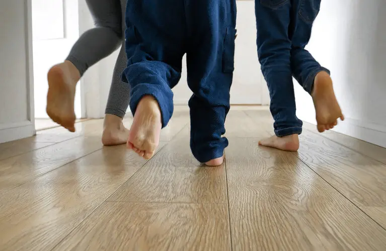 Barefoot family running down a hallway on light oak wood-look vinyl floors.
